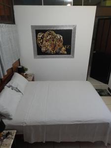 Una cama blanca en una habitación con una foto en la pared en HABITACIÓN AMUEBLADA Y ACOGEDORA, en Puerto Callao