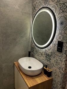 La salle de bains est pourvue d'un lavabo blanc et d'un miroir. dans l'établissement Apartament Kamienica Loft, à Kudowa-Zdrój