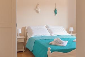 a bed with a blue blanket and towels on it at Ancóramare in Stintino