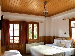 a bedroom with two beds and two windows at Apostolos Hotel in Metsovo