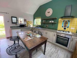 a kitchen with a wooden table and a green wall at The Milking Parlour in Collinstown