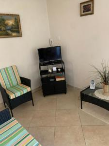 a living room with two chairs and a flat screen tv at Seawinds Apartments in Christ Church