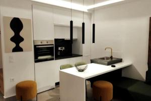 a kitchen with a white island with chairs and a sink at Ρομαντική απόδραση με Χαμάμ in Athens