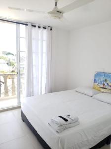 um quarto branco com uma cama grande e uma janela grande em Alojamiento Turístico Verano Azul San Andrés em San Andrés