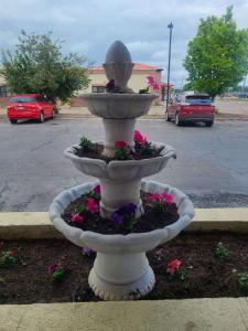 a white fountain with flowers in a parking lot at Horizon Hotel in Vernal