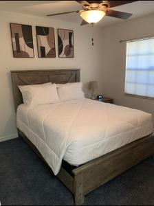 - une chambre avec un grand lit blanc et un ventilateur de plafond dans l'établissement Florida Oasis, à Auburndale