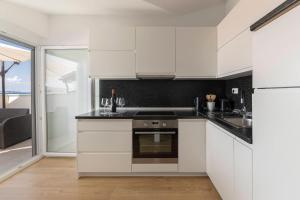 a kitchen with white cabinets and a stove top oven at Apartments ERA Ankaran in Ankaran