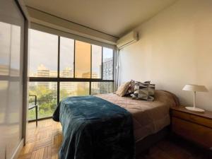 a bedroom with a bed and a large window at Acogedor mono en Plaza Entrevero in Montevideo