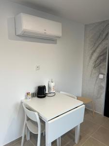 a white kitchen with a table and two chairs at L'Etape, logement climatisé ! in Beire-le-Châtel