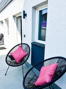 dos almohadas rosas sentadas en dos sillas frente a un edificio en Qonroom - as individual as you - Minden Kaiserstrasse, en Minden
