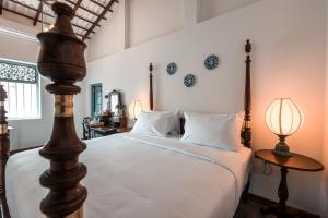 a bedroom with a bed with white sheets and two lamps at Moi Talpe by DBI in Talpe