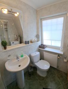 Un baño con lavabo, inodoro y espejo. en Apartament Roma, en Świnoujście 5 fotos más