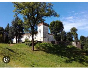 Castiglione Olona的住宿－Appartamento BELVEDERE，山丘上的一座建筑,田野里有一棵树