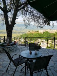 un patio con mesa, sillas y un árbol en Panoramic Vlachos en Gjirokastër