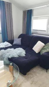 a blue couch in a living room with a glass table at Komfortzone - stilvolle Gästewohnung in Marburg in Marburg an der Lahn