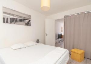 a white bedroom with a bed and a yellow stool at Appartement Zen à Chalon-sur-Saône in Chalon-sur-Saône