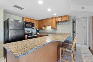 a kitchen with a granite counter top and wooden cabinets at The Beach Club at St. Augustine in Saint Augustine Beach