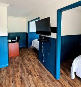 1 dormitorio con paredes azules, TV y cama en The Voy, en Schreiber