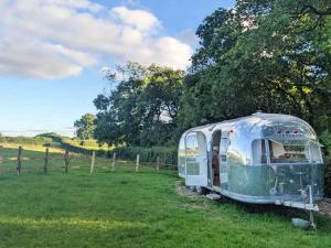 an old trailer sitting in a field next to a fence at Airstream, vintage American caravan & Hottub in Ashburton