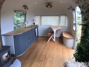 a kitchen with a sink and a desk in a tiny house at Airstream, vintage American caravan & Hottub in Ashburton