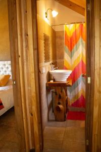 Un baño con lavabo y un perro debajo. en cabañas la arqueria candelaria en Villa Meliquina