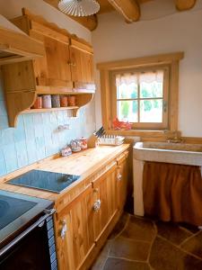 cocina con armarios de madera, fregadero y ventana en Baita dei Fovi, en Baselga di Pinè