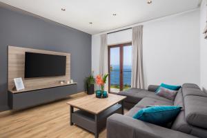 een woonkamer met een bank en een flatscreen-tv bij APARTMAN UHAČ in Mošćenička Draga