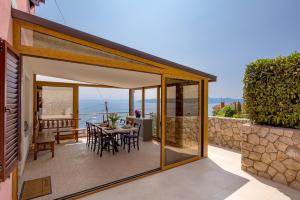 een glazen uitbreiding van een huis met een tafel en stoelen bij APARTMAN UHAČ in Mošćenička Draga