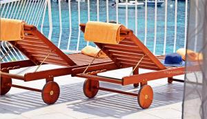 a wooden beach chair with a hat on it next to a pool at Villa Ana Apartments in Molunat