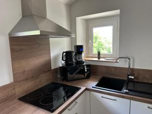 a kitchen with a stove top oven next to a window at Le Chalet - Appartement 5 personnes avec parking in Savignac-les-Ormeaux