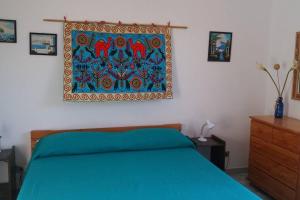 a bedroom with a blue bed and a painting on the wall at Casa Catalogna , Vicino al centro storico. in Lipari