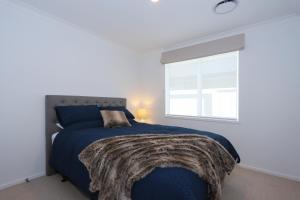 ein Schlafzimmer mit einem blauen Bett und einem Fenster in der Unterkunft Papamoa Coastal Luxury in Papamoa