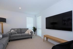 a living room with a couch and a large flat screen tv at Papamoa Coastal Luxury in Papamoa