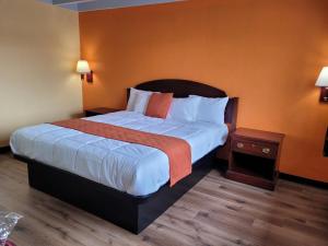 Habitación de hotel con cama grande y paredes de color naranja en Espana Motel en Norwalk