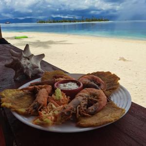 un piatto di pesce su un tavolo sulla spiaggia di hospedaje en las islas de San blas habitacion privado con baño compartido a Achoertupo