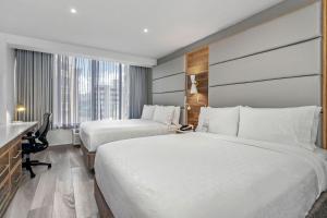 サンファンにあるホリデイ イン エクスプレス サン フアン コンダドのベッド2台とデスクが備わるホテルルームです。