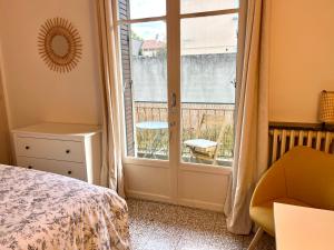 a bedroom with a bed and a window and a chair at Bel appartement lumineux et calme à 10min à pied du centre Aix avec parking in Aix-en-Provence