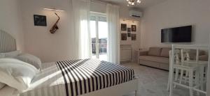 a bedroom with a bed and a tv and a couch at Colombo 477 Stanze Jazz, Soul, Classica in Civitanova Marche