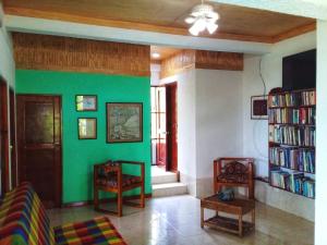 ein Wohnzimmer mit einer grünen Wand mit Büchern in der Unterkunft Windy View Guest House in Providencia