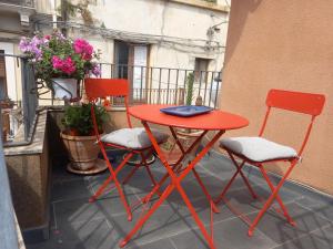 una mesa roja y 2 sillas en el balcón en La sartoria, en Centuripe