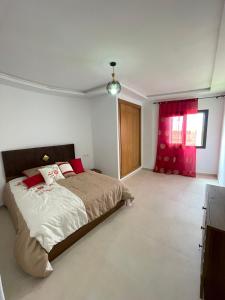 1 dormitorio con 1 cama grande y cortina roja en Résidence Colina Smir, en M'diq