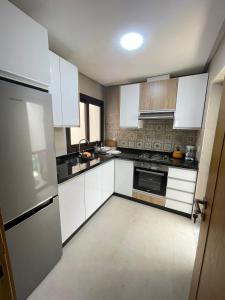 a kitchen with white cabinets and a stove top oven at Résidence Colina Smir in M'diq