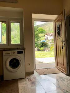 uma máquina de lavar roupa num quarto com uma porta aberta em Casa particular en Renedo de Cabuérniga em Renedo