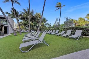 una fila de tumbonas en un césped con palmeras en Modern Miami Beach Condo with Beach Service & Pool, en Miami Beach