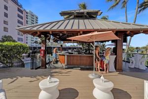 un cenador con un bar con gente de pie bajo él en Modern Miami Beach Condo with Beach Service & Pool, en Miami Beach