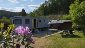 ein winziges Haus mit einem Picknicktisch und einem Regenschirm in der Unterkunft Le Beau Rivage - M24 in Trois-Ponts