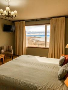 a bedroom with a large bed and a large window at Hosteria La Estepa in El Calafate