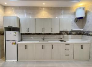 a kitchen with white cabinets and a white refrigerator at Comfort Stay in Taif