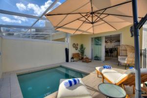 a swimming pool with an umbrella and chairs and a patio at Placid Retreat Near Disney Orlando, FL in Orlando
