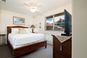 a bedroom with a bed and a flat screen tv at 3bd 3ba Oceanview Condo w Office and AC and WIFI and Garage ACAA1 in Kailua-Kona
